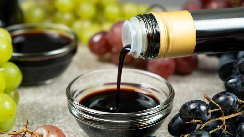 Balsamic vinegar pouring out of bottle into ramekin