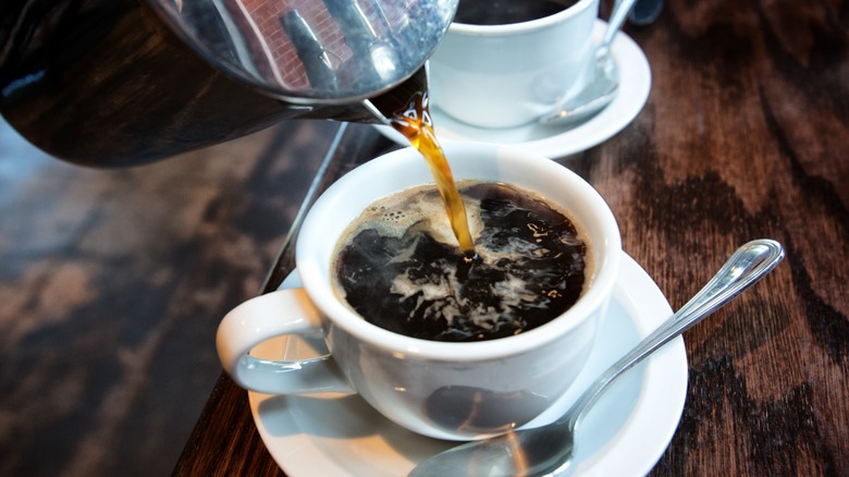 Coffee being poured into white coffee cup.
