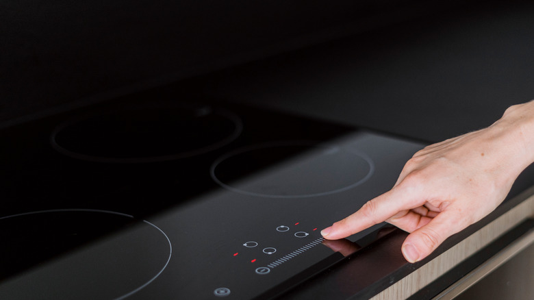 Hand turning on induction stovetop
