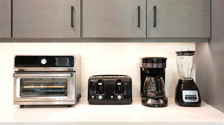 Toaster oven, toaster, coffee maker, and blender on kitchen counter.
