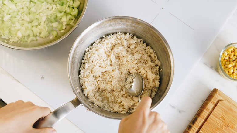 Pot of white rice next to a bowl of chopped celery and a bowl of corn