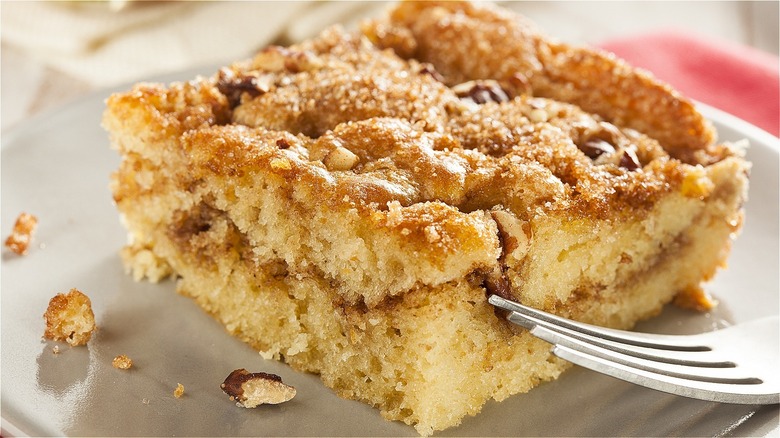 A slice of crumbly coffee cake on a plate with a fork