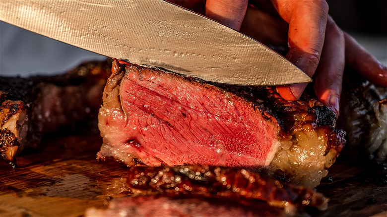 person cuts steak