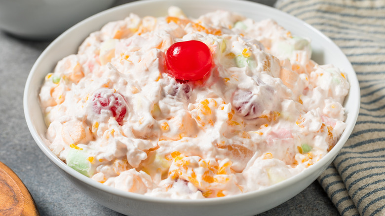 Close-up of an ambrosia salad with a cherry on top in a white bowl