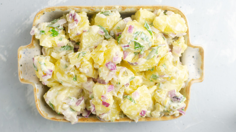 Thick potato salad with red onion in a vintage dish