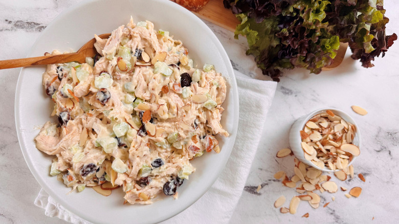 Chicken salad in bowl next to small bowl of sliced almonds