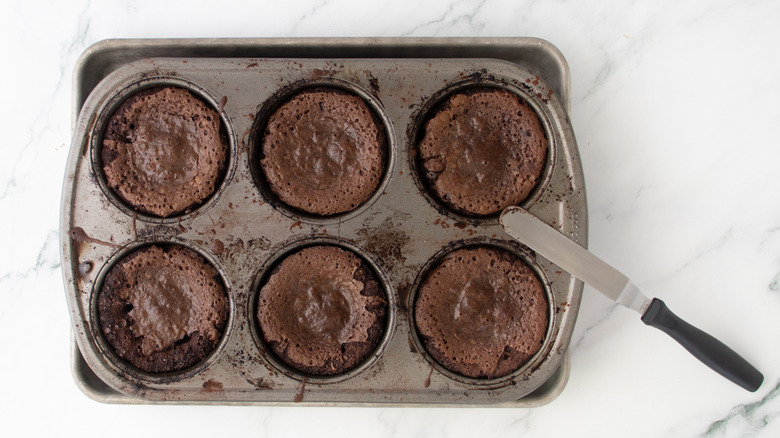 chocolate cake in a muffin pan with a knife