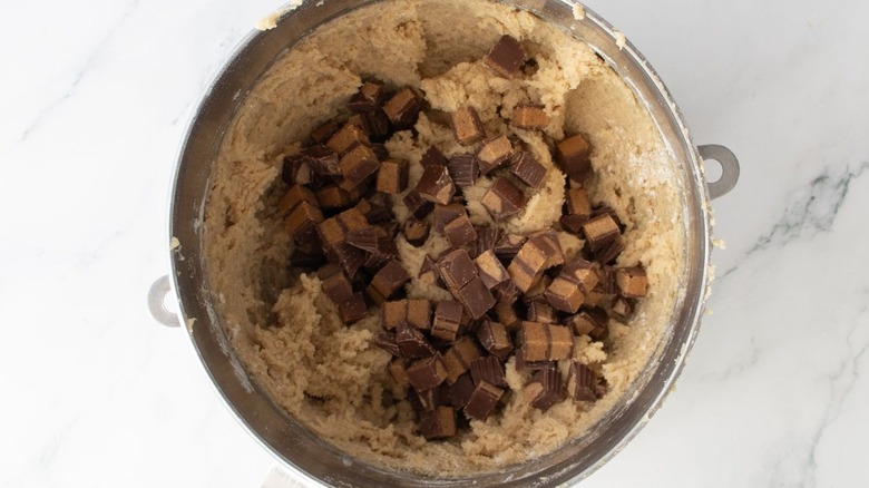 Cookie dough and chopped peanut butter cups in mixing bowl