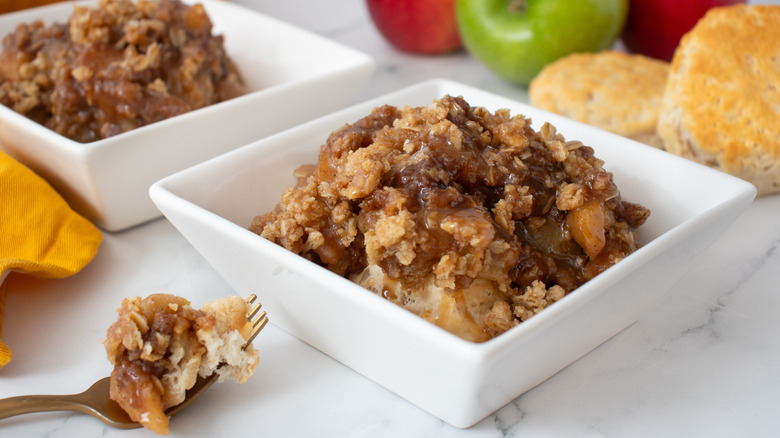 cooked apples with crumbly brown topping in two square white bowls