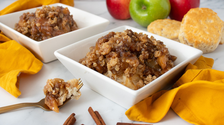 cooked apples with crumbly brown topping in two square white bowls