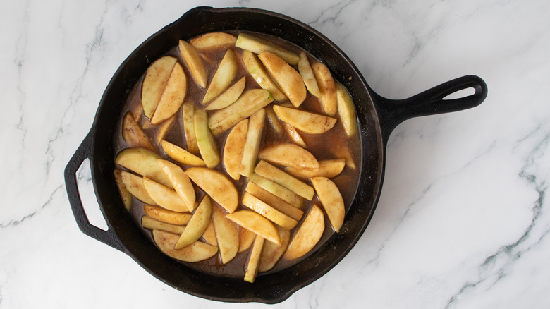 sliced apples and brown liquid in a black frying pan