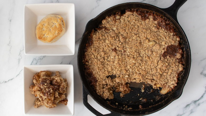 biscuits in two square white bowls next to a pan of baked oat mixture