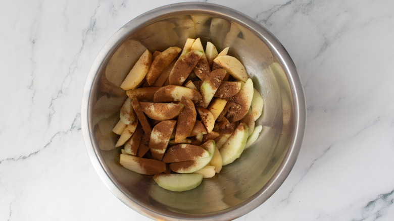 sliced apples and cinnamon in a metal bowl