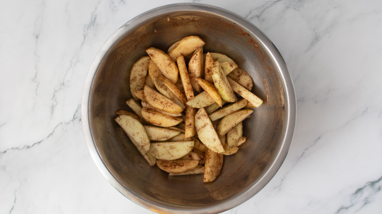 sliced apples and cinnamon in a metal bowl