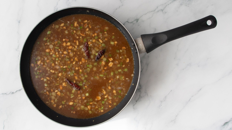 Sauce, minced aromatics, and dried chiles in pan