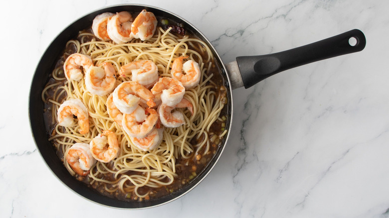 Shrimp and spaghetti in pan on top of sauce
