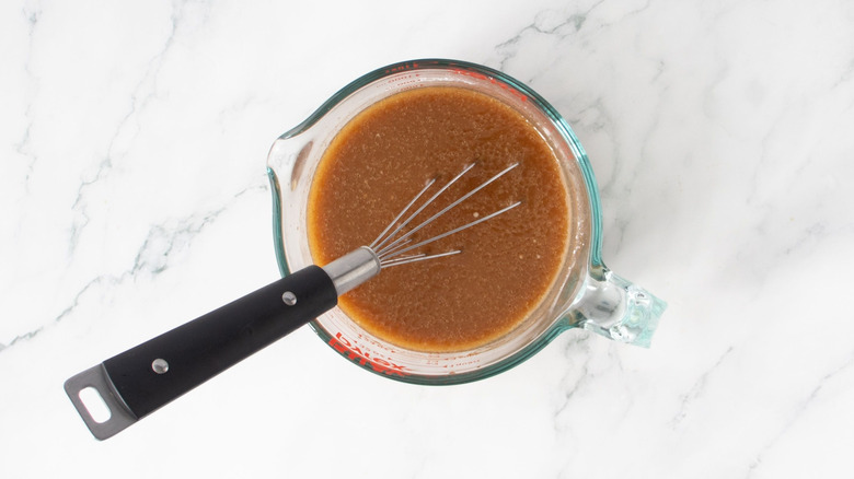 Whisk and brown sauce in measuring cup