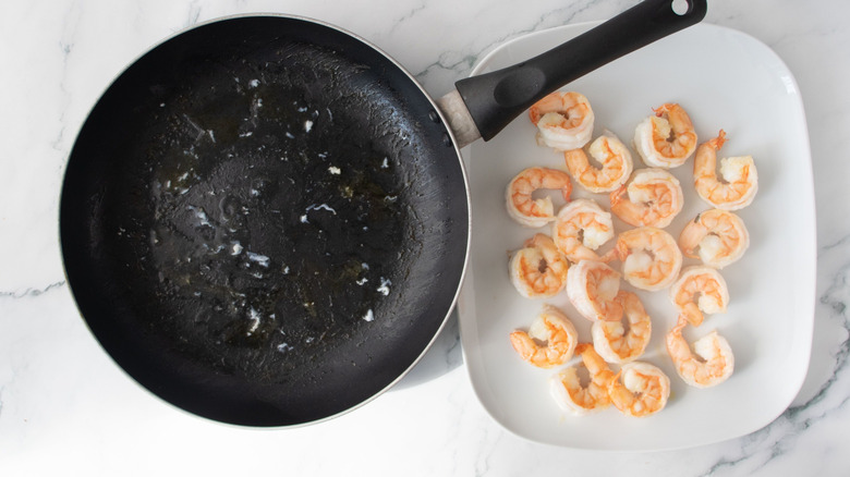 Empty pan next to shrimp on plate