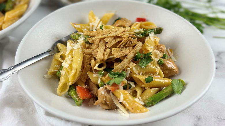 chicken, vegetables, and noodles in a white bowl with a fork