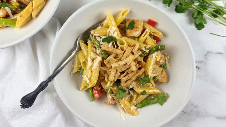 chicken, vegetables, and pasta in a white bowl with a fork