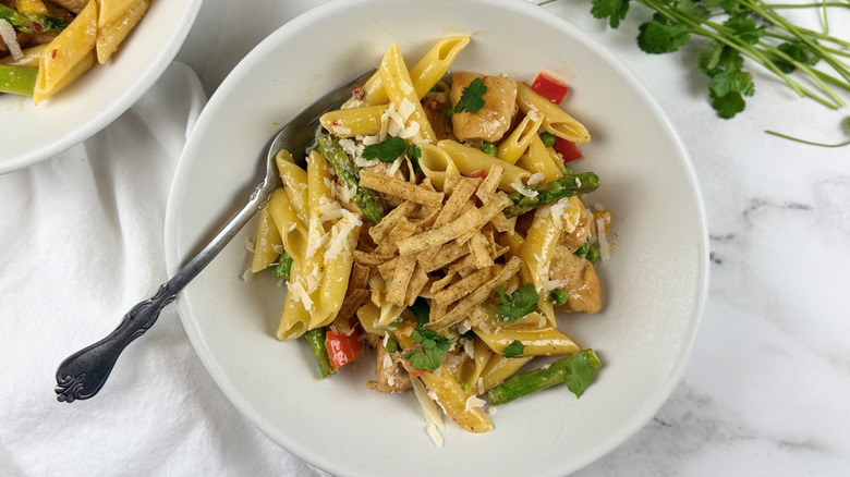chicken, vegetables, and pasta in a white bowl with a fork