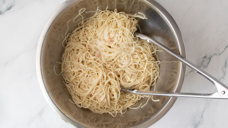 Angel hair pasta in bowl with tongs