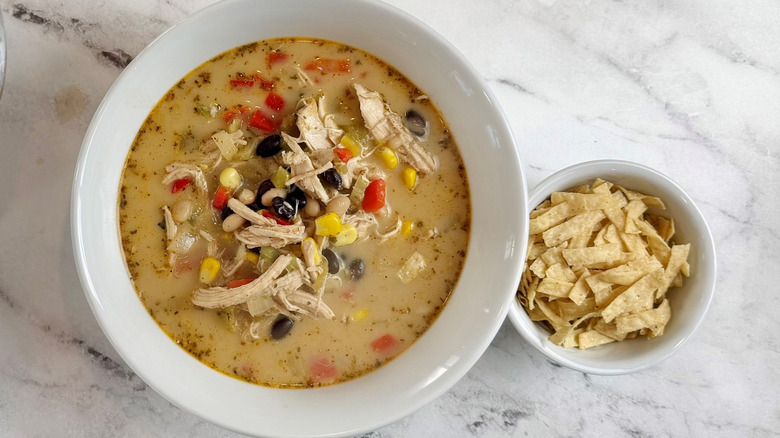 Bowl of chicken tortilla soup next to bowl of tortilla strips