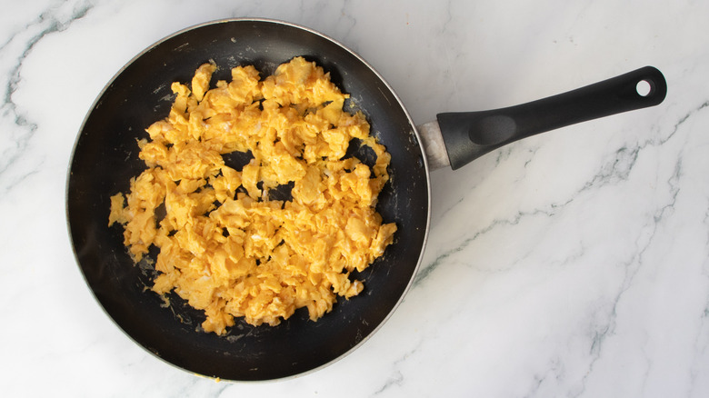 black frying pan filled with scrambled eggs on a kitchen counter