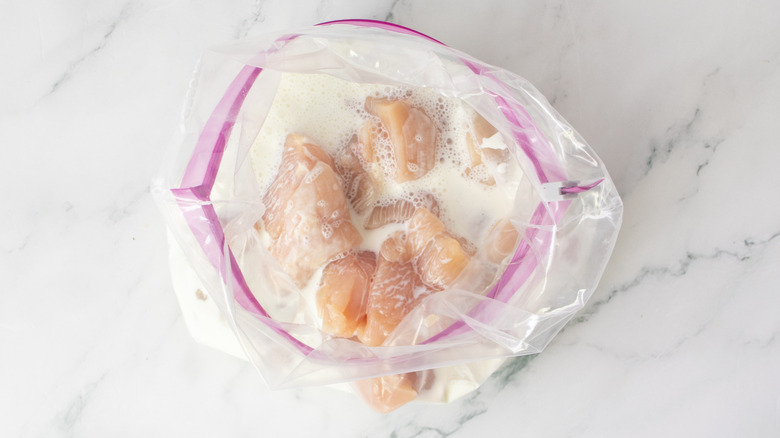 raw chicken and white liquid in a plastic bag