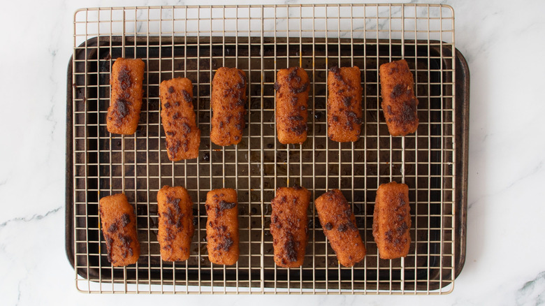 Mozzarella sticks coated in sauce on wire rack