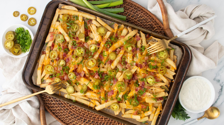 Chili's Texas cheese fries on baking sheet with ranch dip, jalapeños, and green onions
