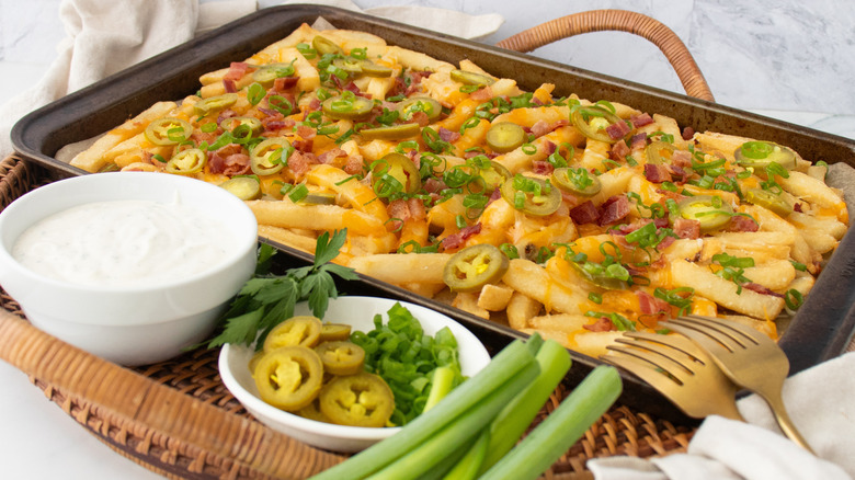 Chili's Texas cheese fries on baking sheet with dip, jalapeños, and green onions