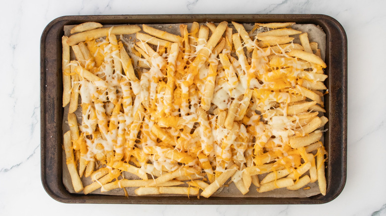 Fries on baking sheet topped with melted cheese