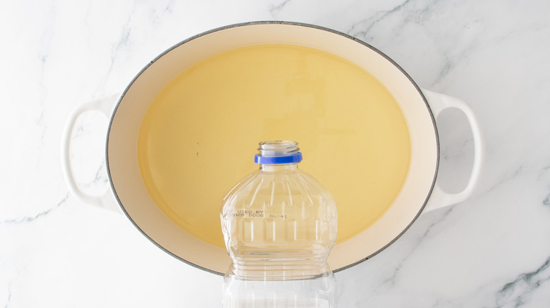 Container of oil pouring into large pot