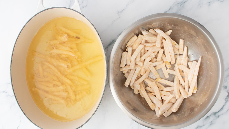 Fries frying in pot of oil next to fries in bowl