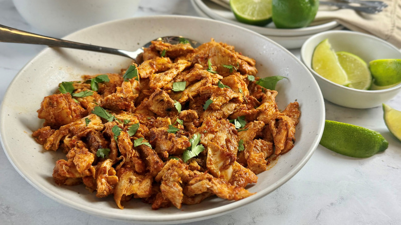 Chicken al pastor in bowl next to lime wedges