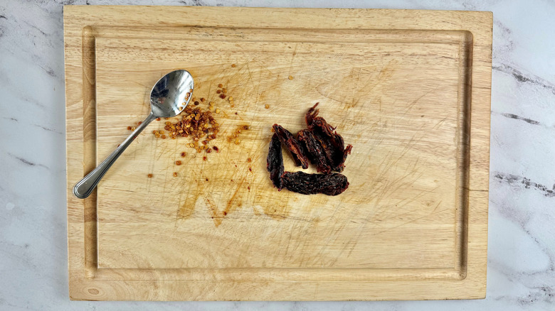 Seeded peppers and spoon on wooden board