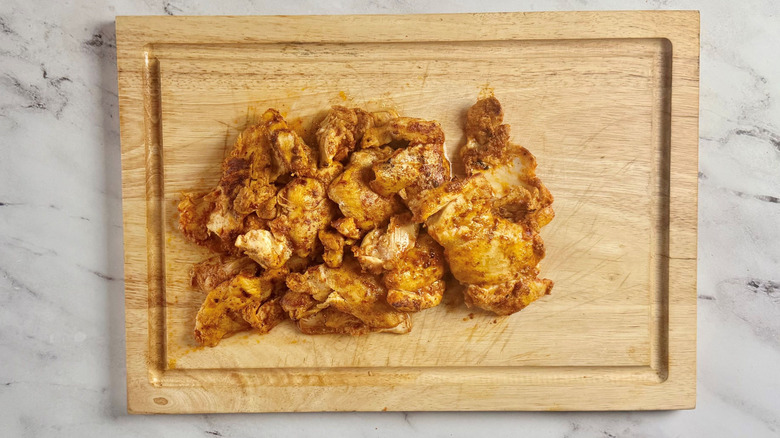Chicken thighs on wooden board