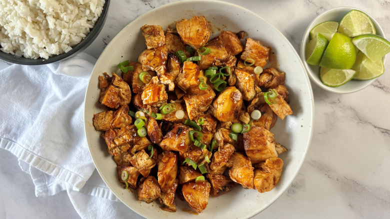 Chipotle honey chicken in bowl next to rice and limes