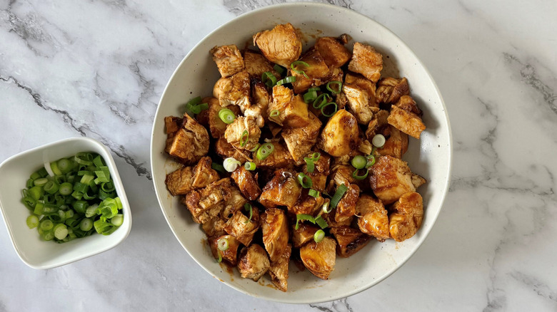 Honey chicken garnished with scallions in bowl