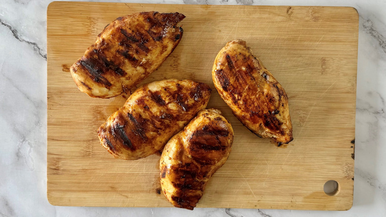 Grilled chicken breasts on cutting board