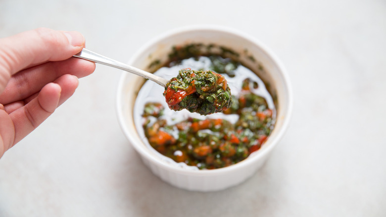 hand holding spoon of chimichurri