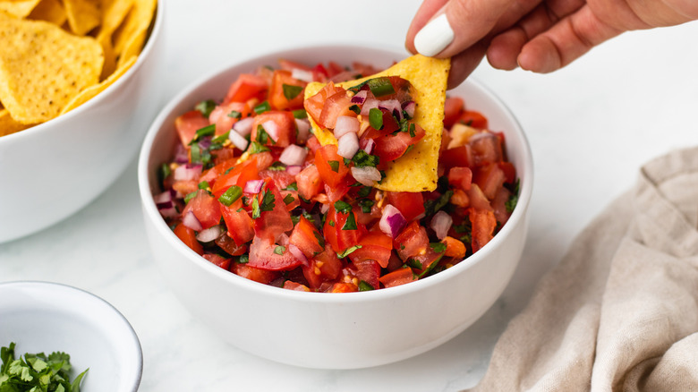 Salsa being scooped with tortilla chip