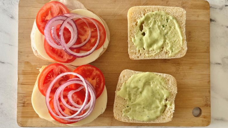 bread topped with green spread, tomatoes, and onions