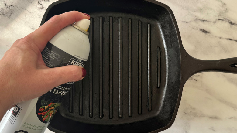 hand holding an aerosol can and spraying a black pan