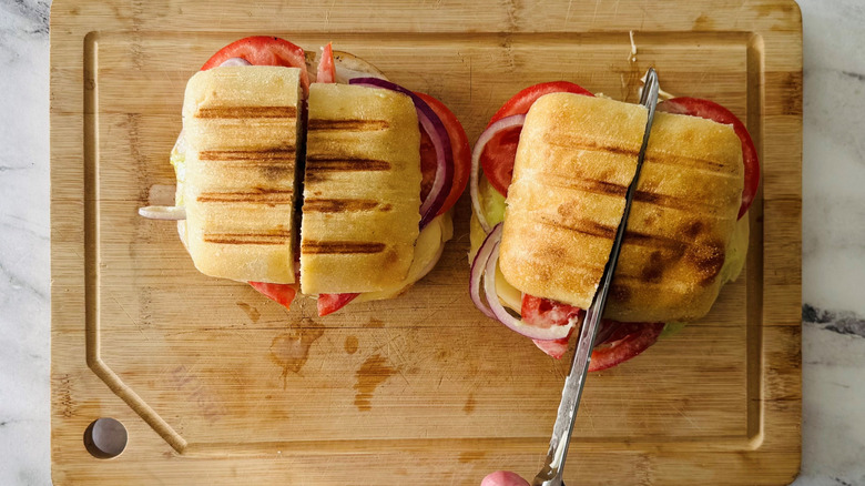 hand cutting a sandwich in half