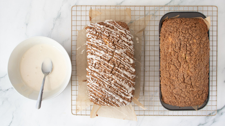 Bowl of icing next to iced and uniced coffee cakes on wire rack