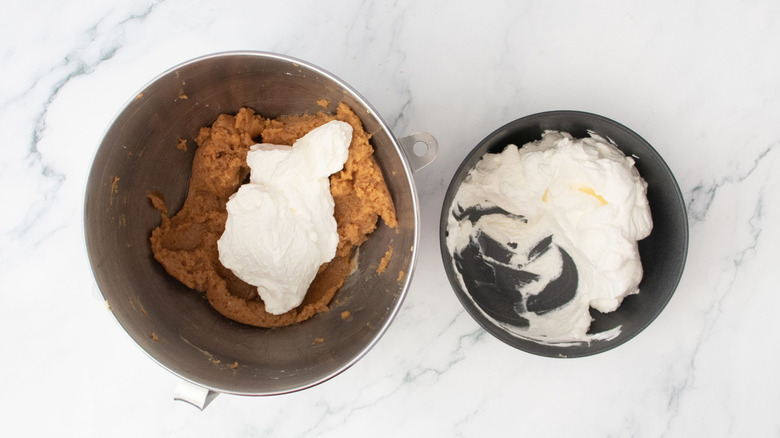 Peanut butter and whipped cream in bowl next to smaller bowl of whipped cream