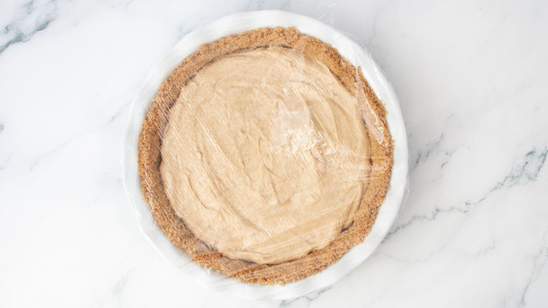 Peanut butter mousse pie covered with plastic wrap