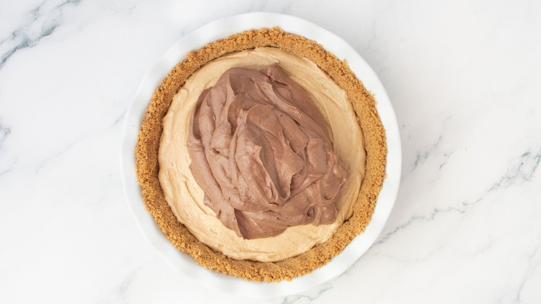 Chocolate mousse mixture on top of peanut butter layer in pie crust